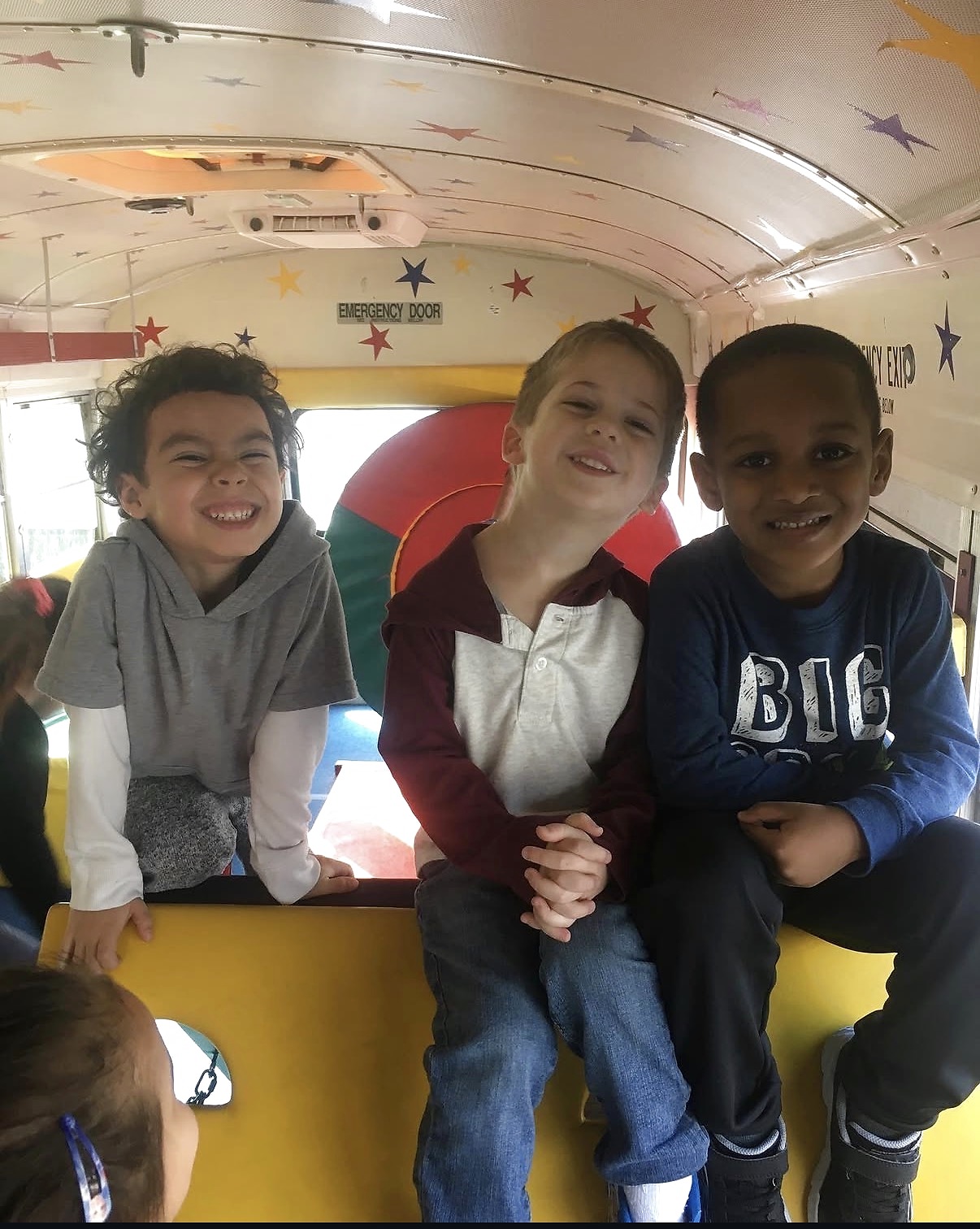 Three smiling children enjoying time inside the Tumblebus